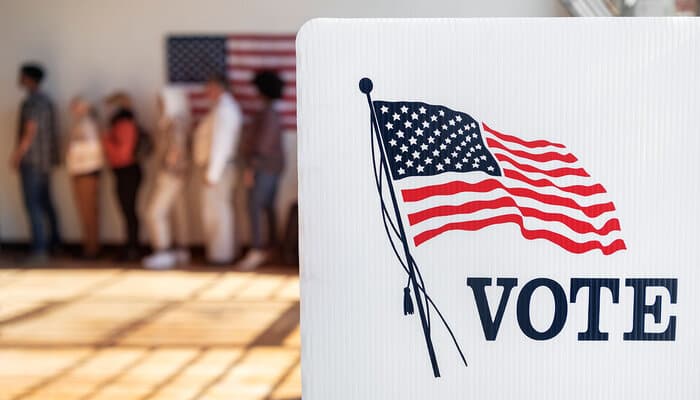 Gavel and American flag beside a stack of voter registration documents